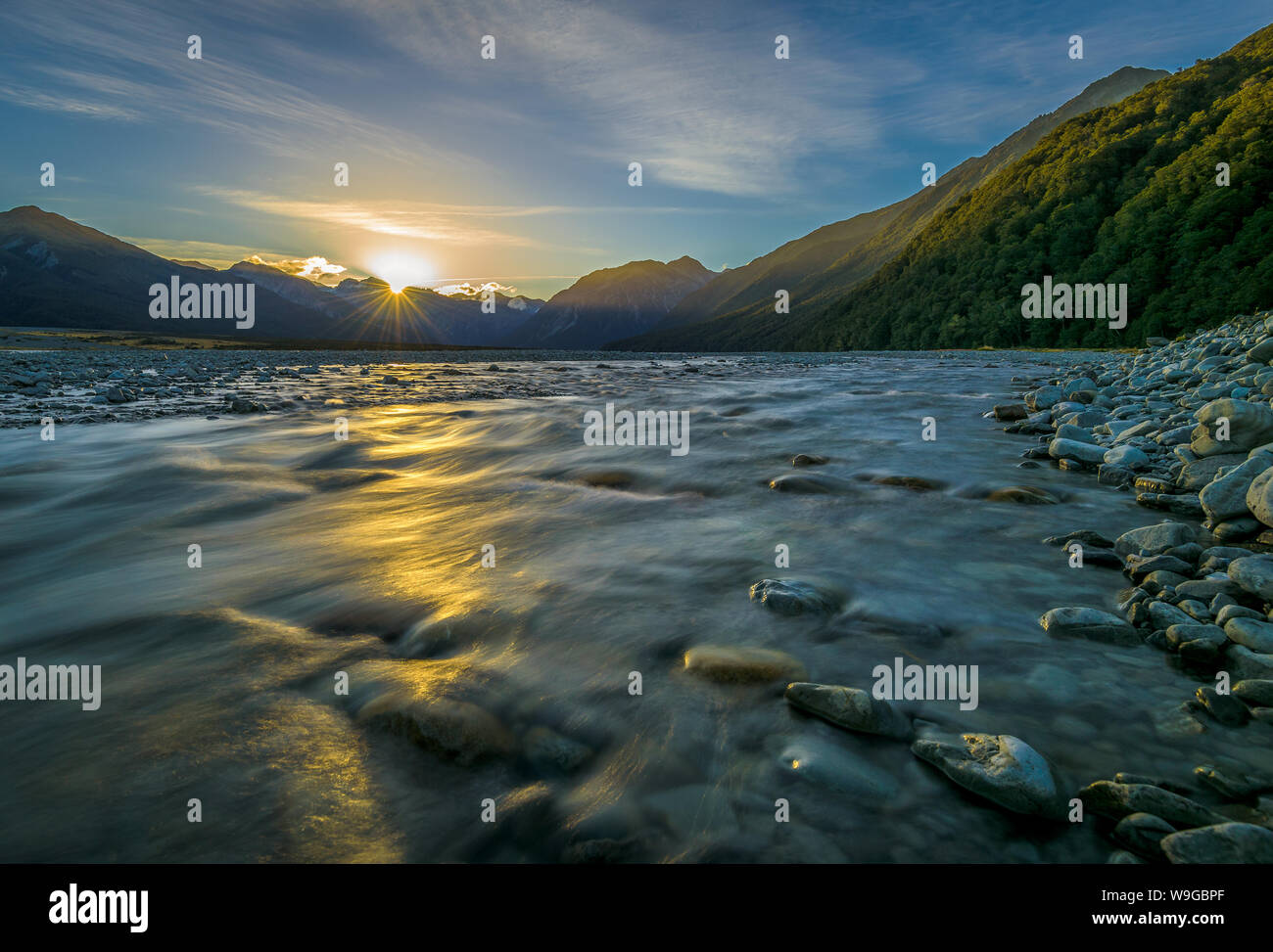 Mit Blick über den Waimakariri-Fluss in Richtung der Berge des Arthur's Pass, Neuseeland, während die Sonne an einem Frühlingstag untergeht. Stockfoto