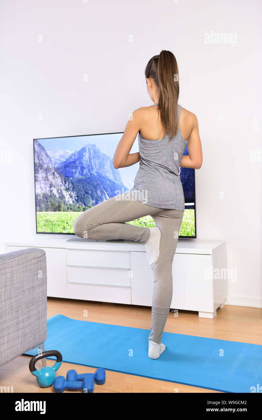 Yoga Video Class - Frau Training zu Hause im Wohnzimmer vor dem Fernseher nach einem fitnessprogramm oder sehen Sie Ihre Lieblings-TV-Show. Stockfoto