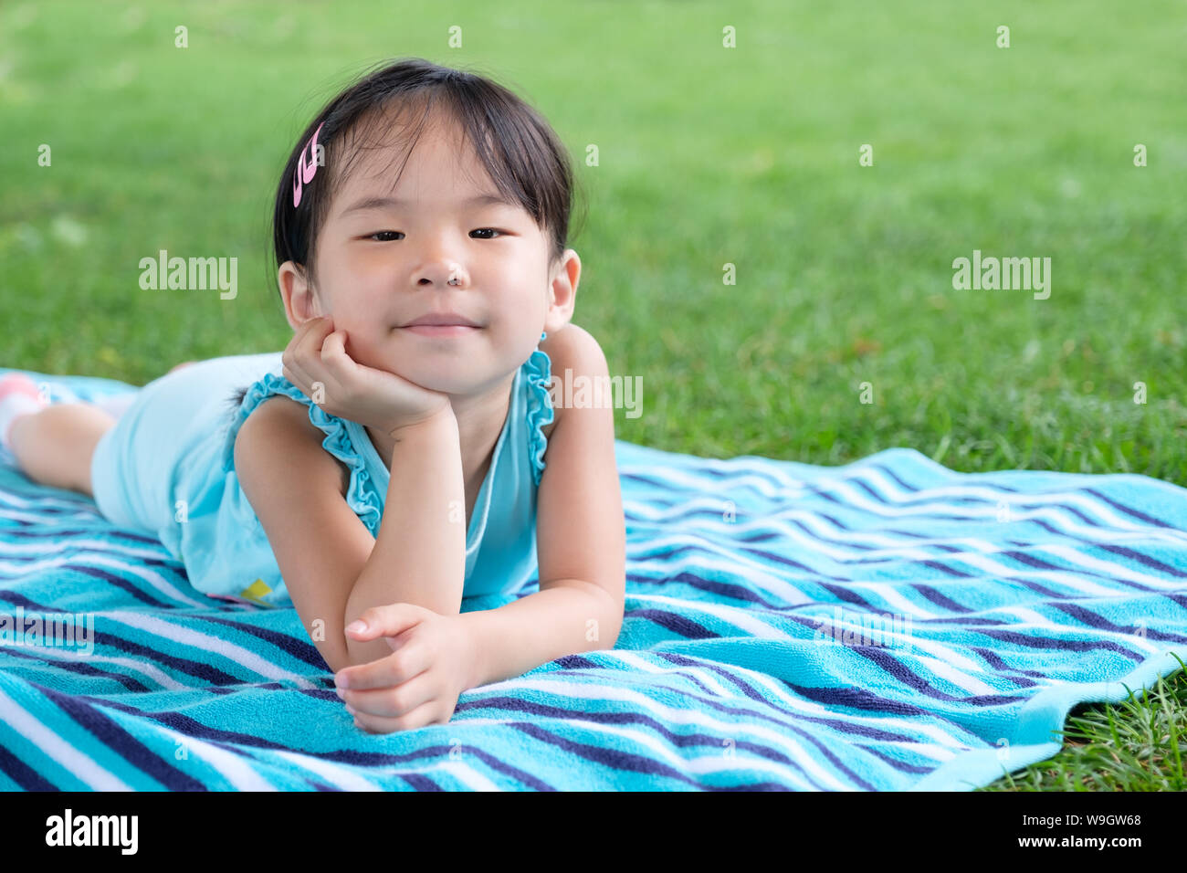 Wenig kleinkind Mädchen mit auf dem Handtuch im Gras im Sommer Stockfoto