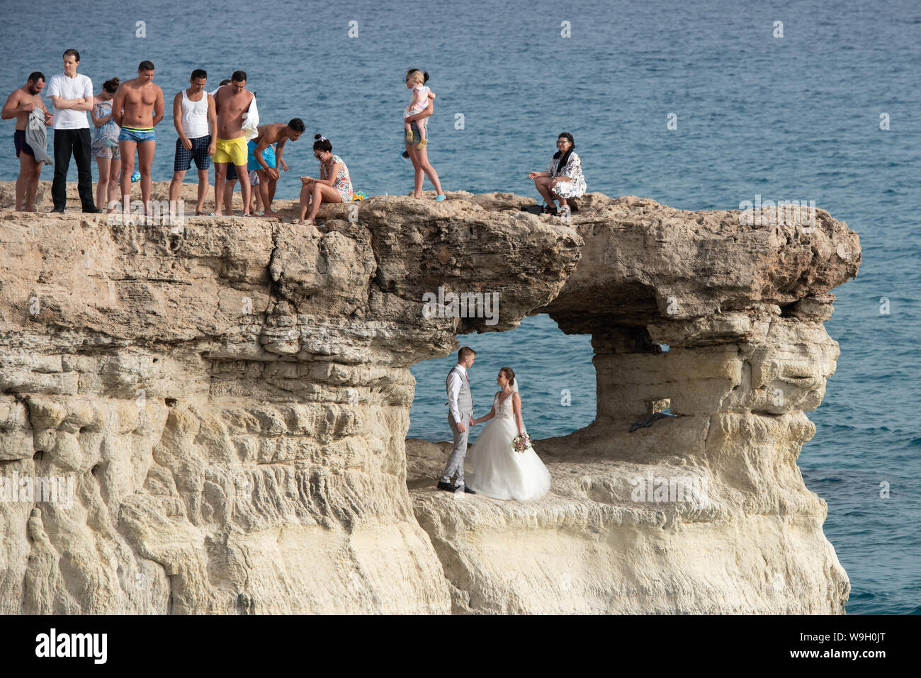 Die Leute stehen und sitzen auf den Felsen und genießen sie das kristallklare Wasser und ein junges Ehepaar Fotografie erhalten Stockfoto