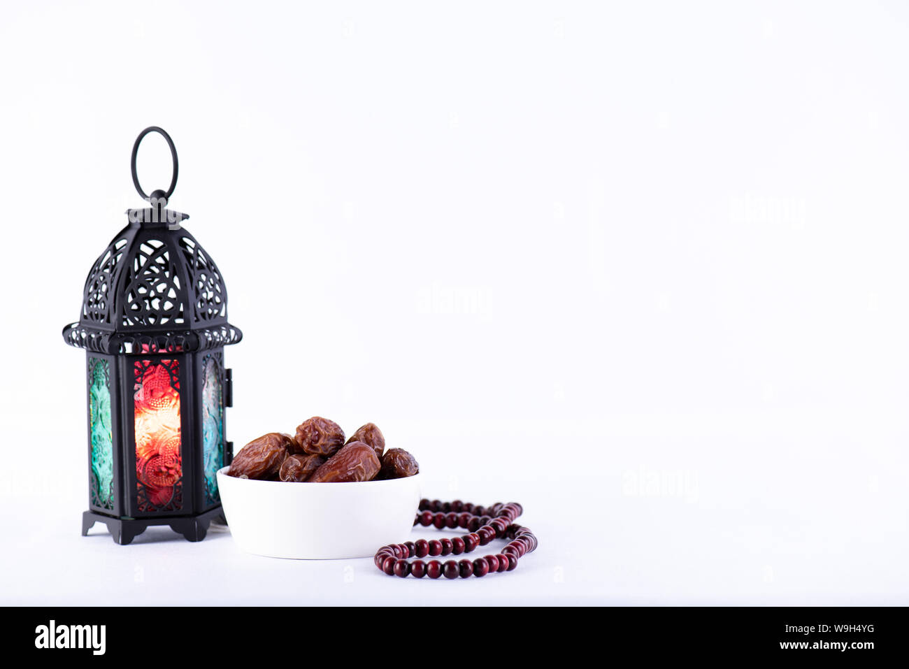 Ramadan Essen und Getränke Konzept. Ramadan Laterne mit arabischen Lampe, Holz Rosenkranz, Kaffee, Obst und Beleuchtung an einem Holztisch auf weißem Hintergrund. Stockfoto