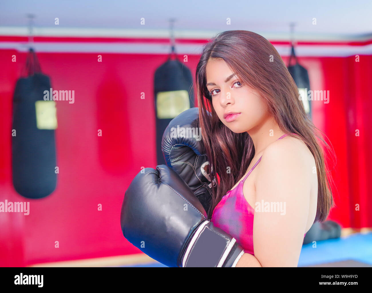 Sportliche Frau mit dunklen Haaren im Sport Handschuhe und lila Outfit für Boxen in den Fitnessraum. Stockfoto