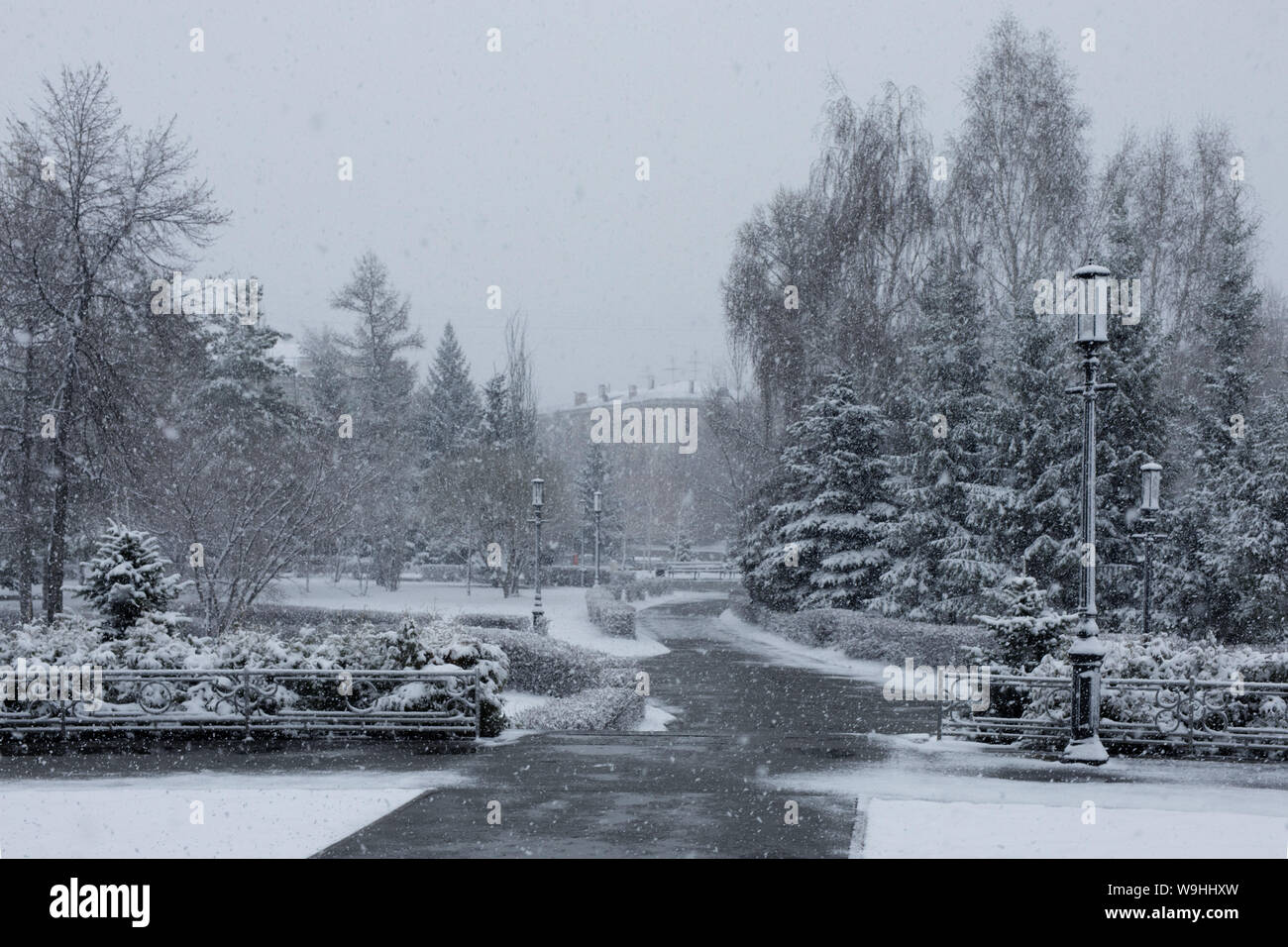 Snowy city street, Park und die Menschen unter dem Schnee. Kam der Winter im Frühsommer. Ungewöhnliche Naturphänomene Stockfoto