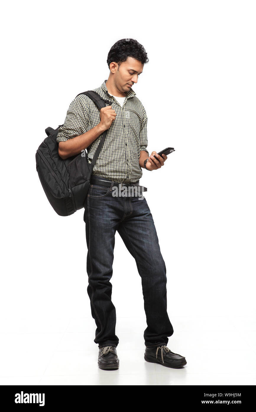 Junger Mann SMS auf einem Handy mit Rucksack Stockfoto