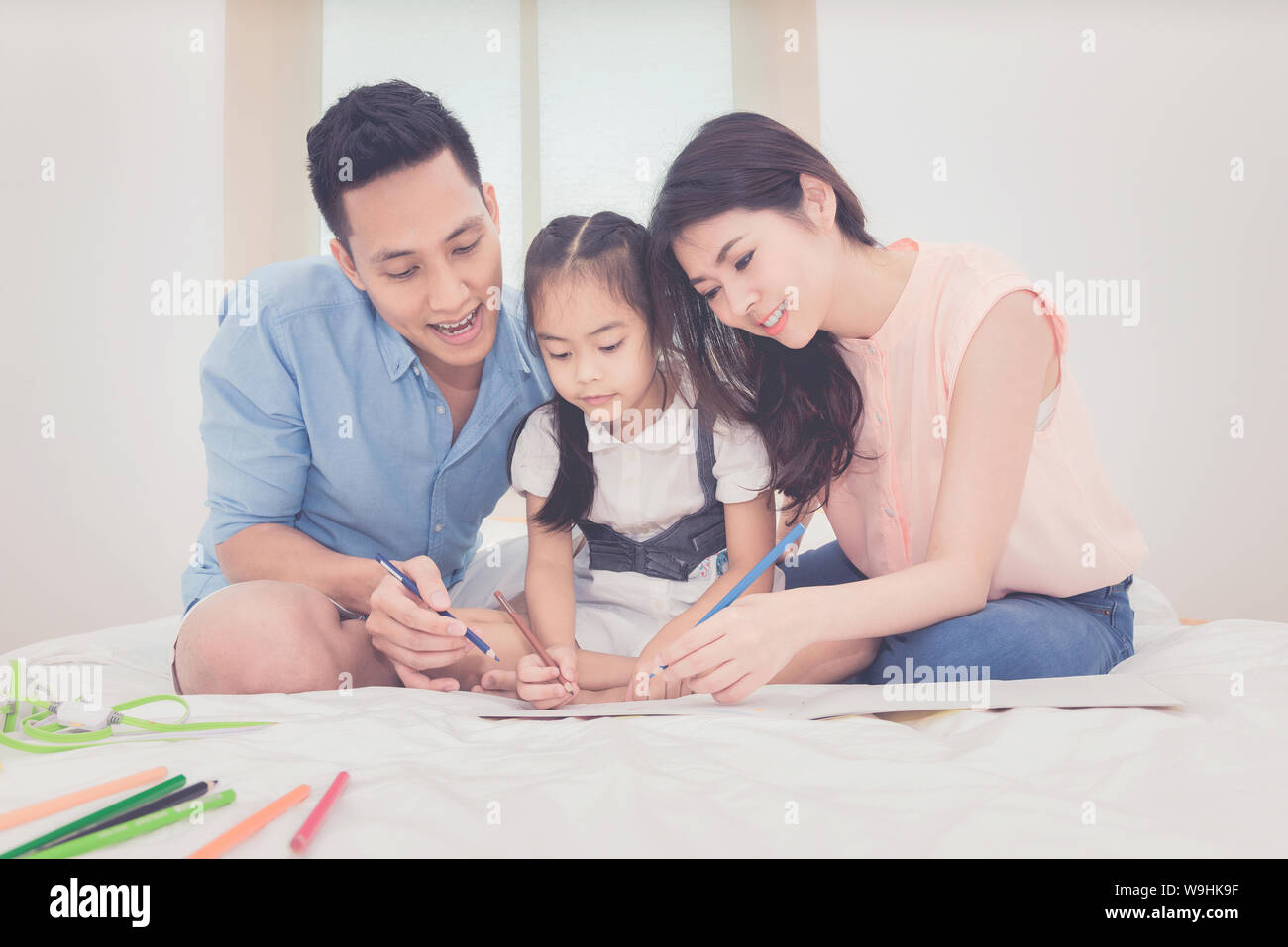 Happy Family im Schlafzimmer, asiatische Vater und Mutter ihre Tochter Kind zu Hause zu studieren. Stockfoto