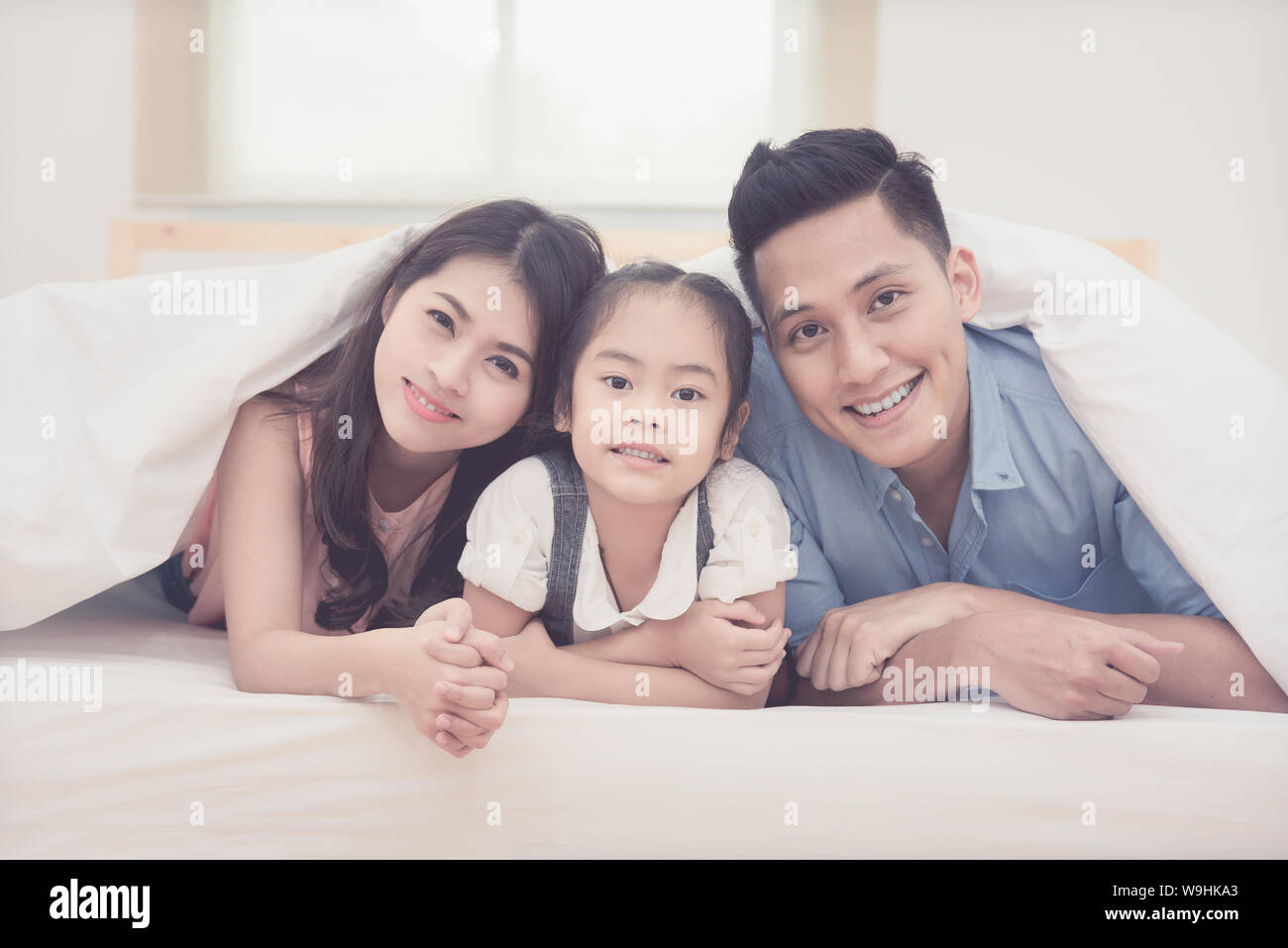 Asiatische Familie glücklich lächelnd und auf dem Bett zu Hause entspannen. Foto serie von Familie, Kindern und glücklichen Menschen. Stockfoto