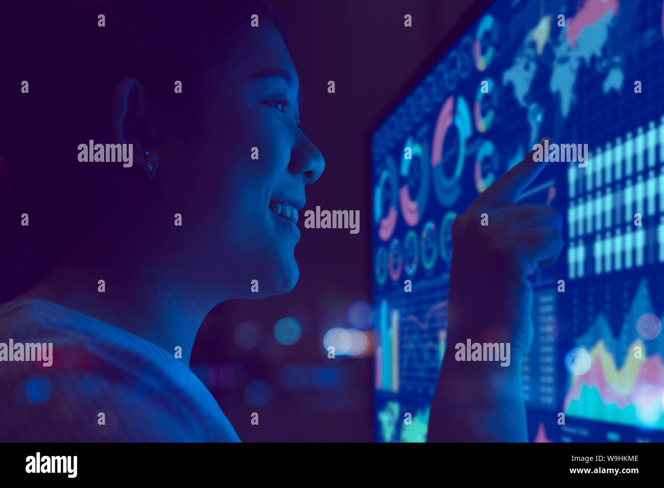 Lächeln business Frauen Finger auf chart Tafel overlay futuristische Tech moderne leader Lifestyle dunkle Nacht Zimmer Stockfoto