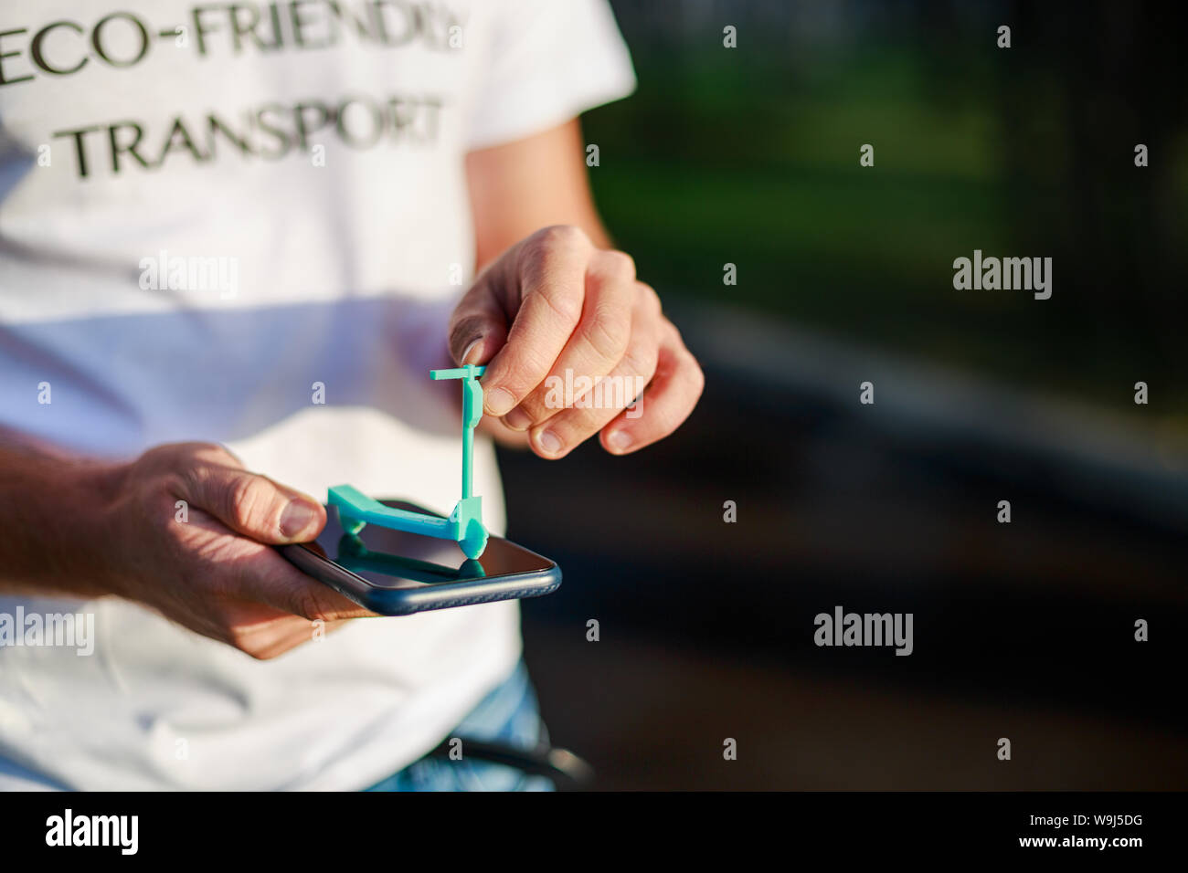 Man Hände nimmt Mini e-Scooter über sein Smartphone t-shirt mit Text umweltfreundliche Verkehrsmittel Stockfoto