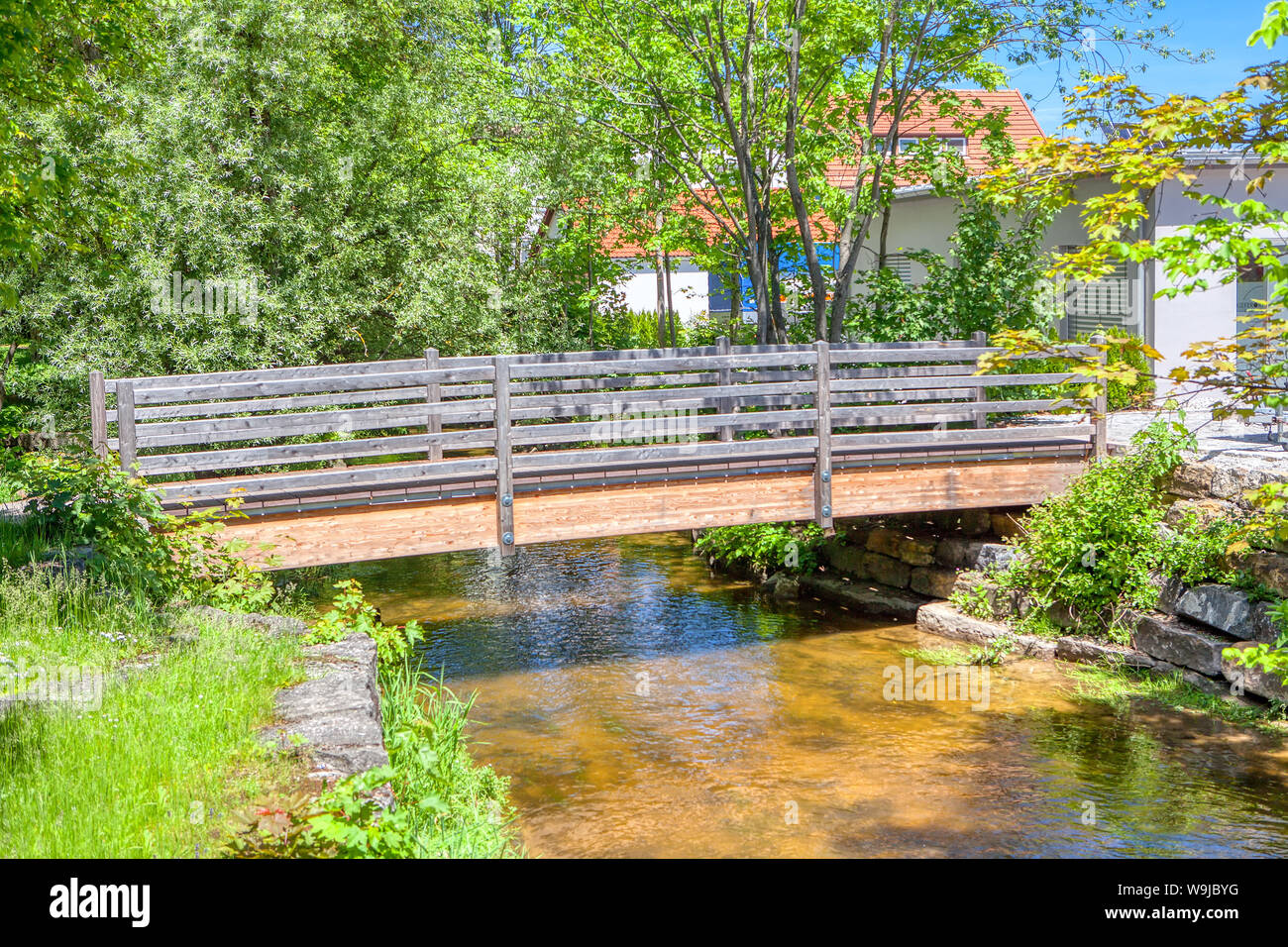 Fußgänger-Holzbrücke über einen kleinen Fluss Stockfoto