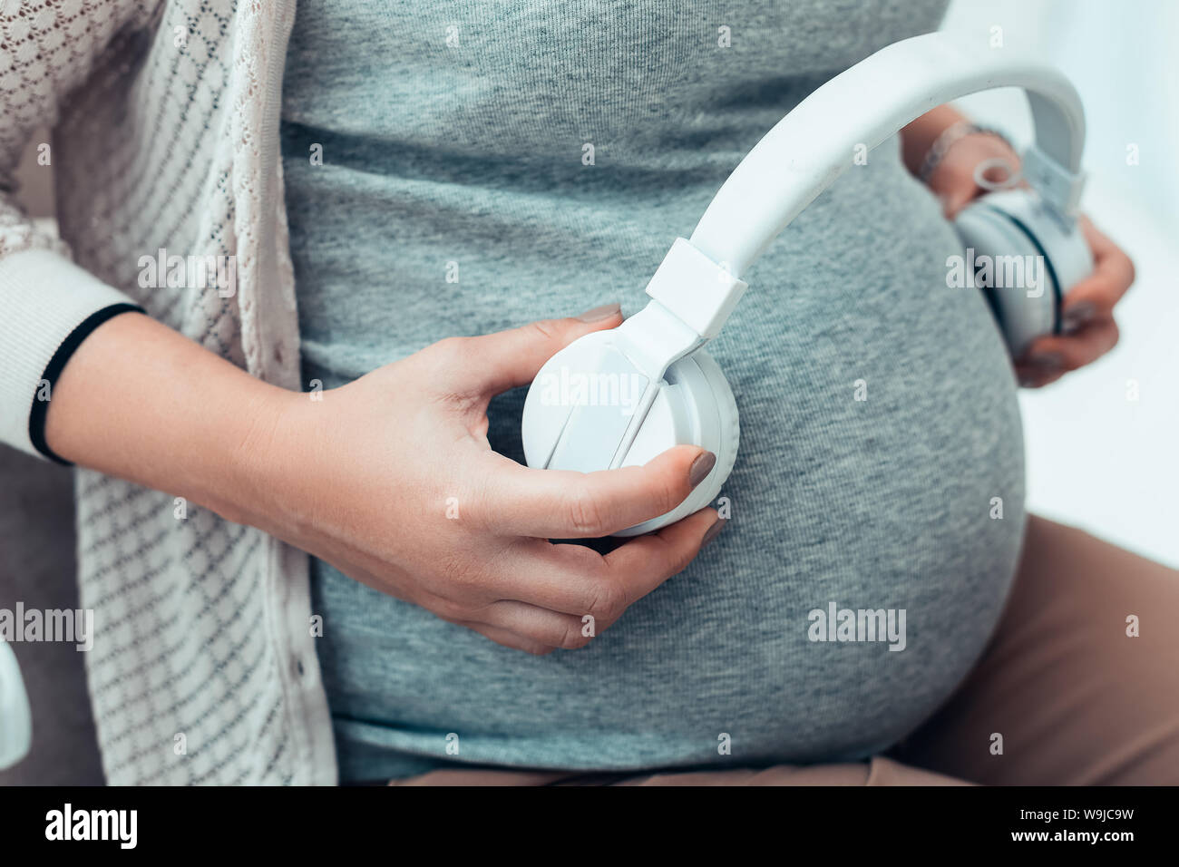 Schwangere Frau Kopfhörer setzen auf ihrem Abdomen Stockfoto