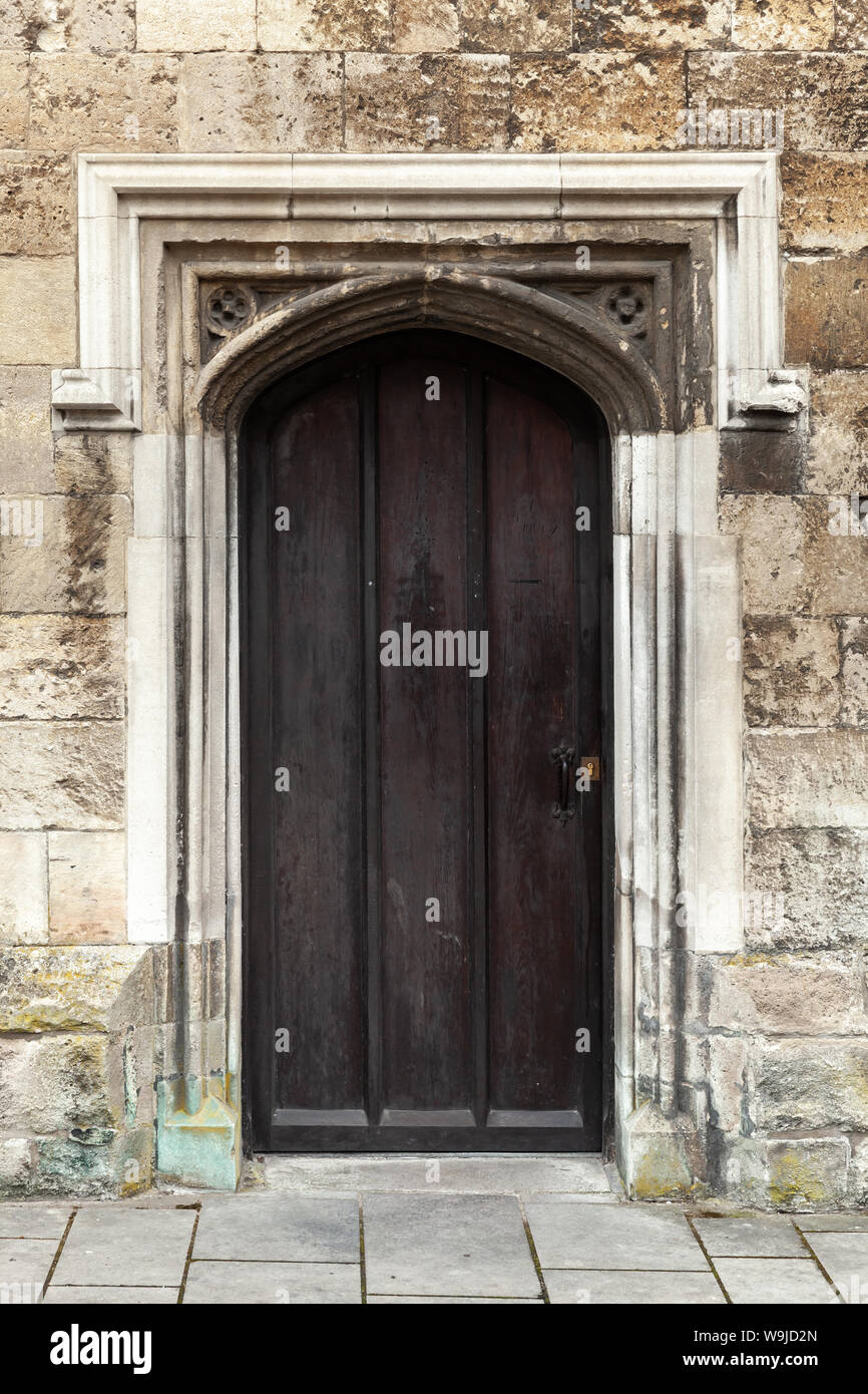 Geschlossene schwarze hölzerne Tür in alten Steinmauer, vertikale Hintergrund Foto Textur Stockfoto
