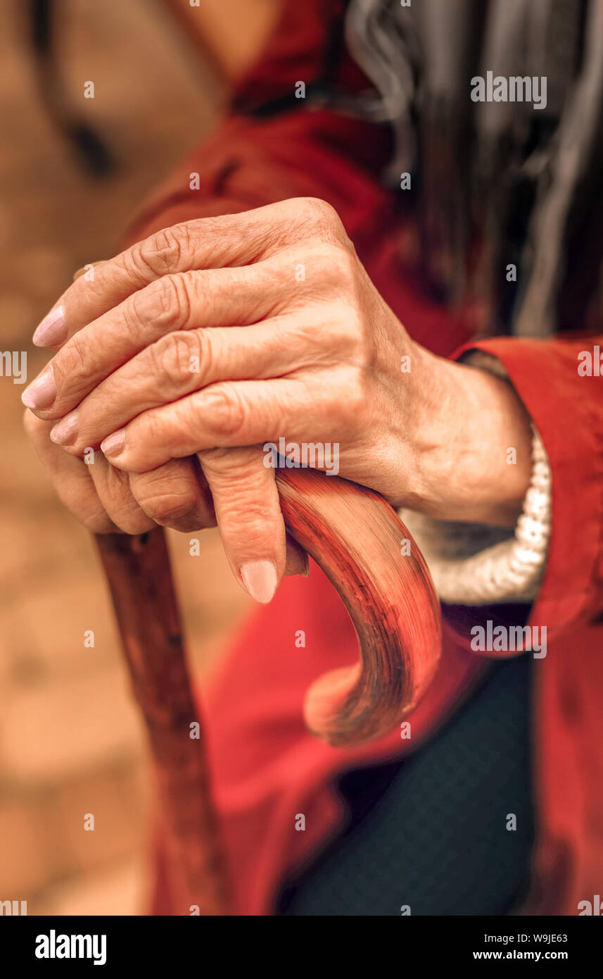 In der Nähe der Hände von einer alten Frau lehnte sich auf Zuckerrohr Stockfoto