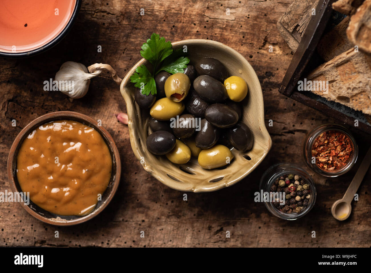 Grüne und schwarze Oliven und andere Häppchen auf hölzernen Tisch Stockfoto