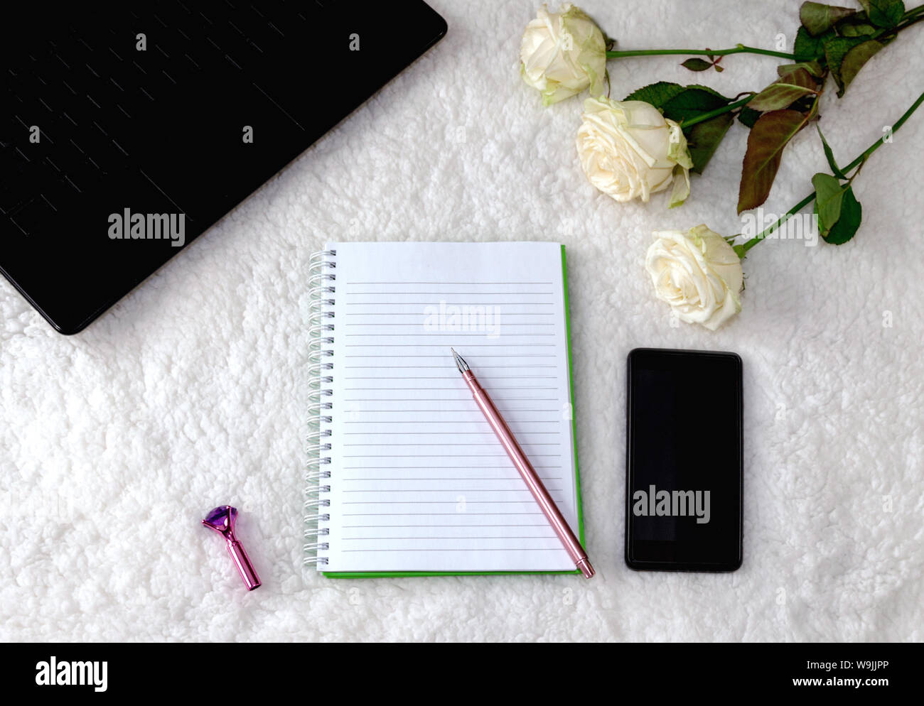 Notepad und schöne Pen auf hellem Hintergrund, weiße Rosen und ein Notebook, geeignet für Hintergrund und Schreiben. Stockfoto