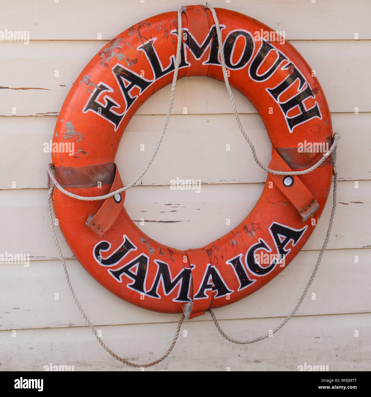 Orange leben Ring mit dem Namen des populären Karibik Kreuzfahrt Hafen von Falmouth, Jamaika malte auf Sie hängen an einem beige lackiert Holz Wand im Quadrat Stockfoto
