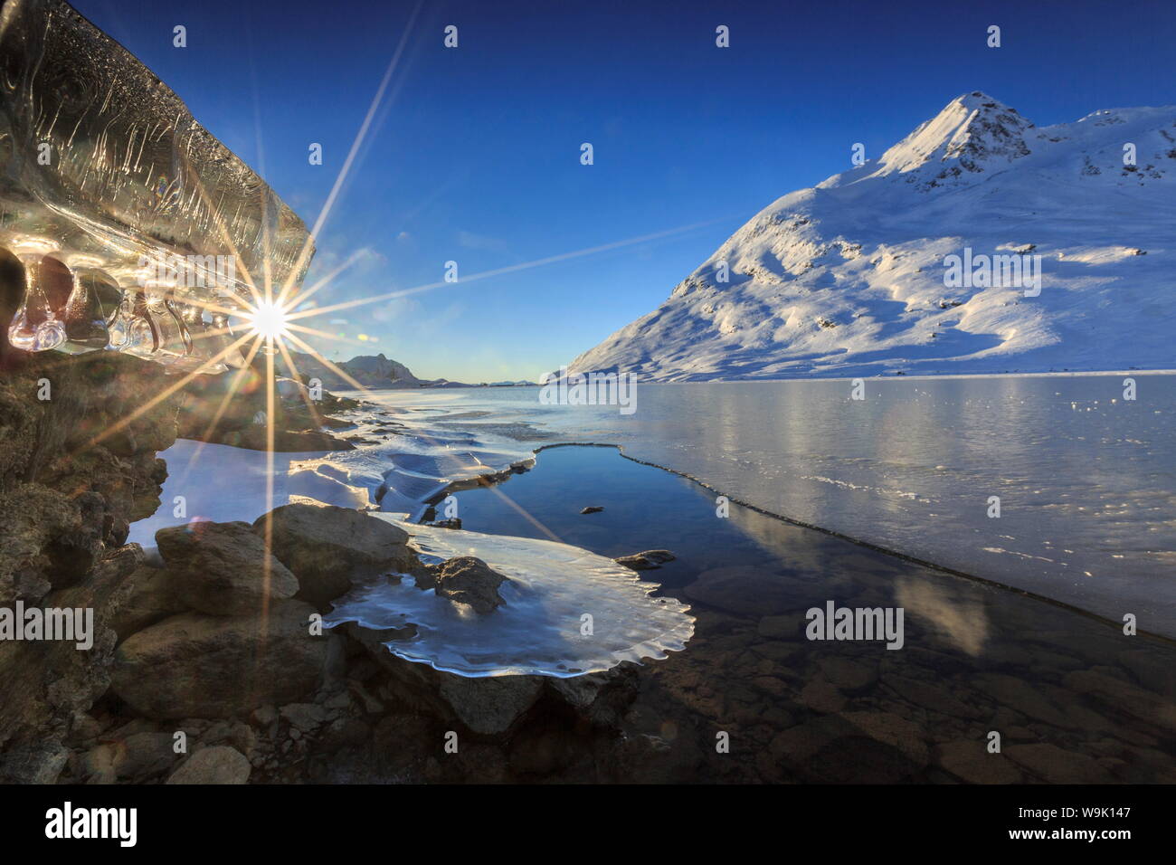Die Sonne durch Eiszapfen an den Ufern des Lago Bianco am Bernina gebildet scheint, vollständig gefroren, Berninapass, Graubünden, Schweiz, Europa Stockfoto
