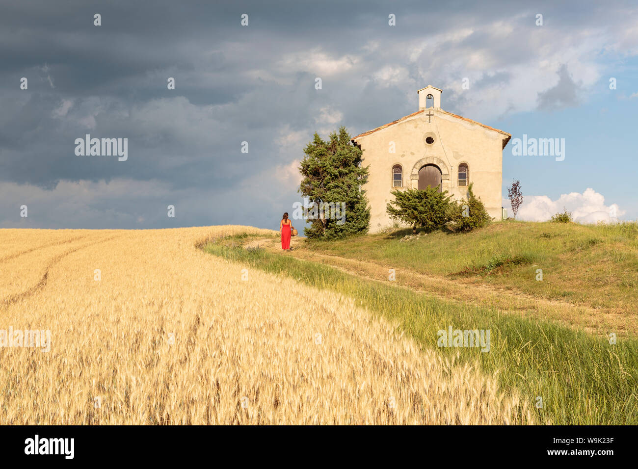 Die Frau im roten Kleid und Weidenkorb vorbei an Notre-Dame-de-Sante Kapelle, Entrevennes, Alpes-de-Haute-Provence, Provence Alpes Cote d'Azur, Frankreich Stockfoto