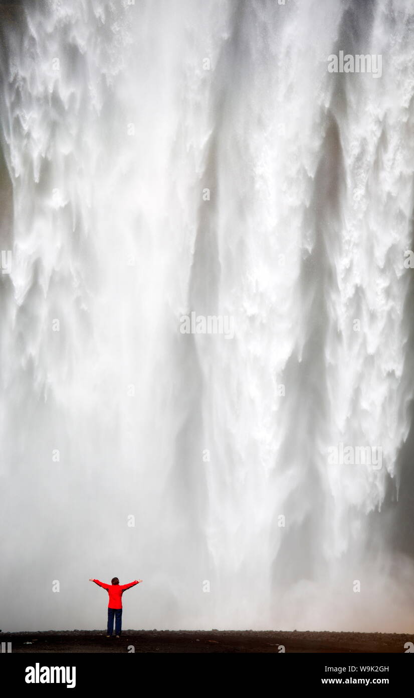 Frau in rot Jacke stand vor Skogafoss Wasserfall, South Island, Island, Polarregionen Stockfoto