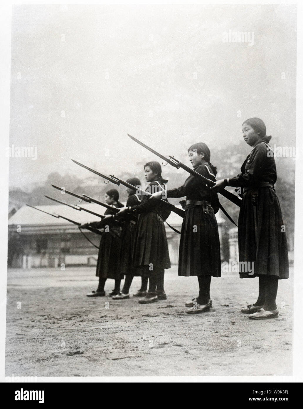 [1930er Jahre Japan - militärische Ausbildung für Japanische High School Mädchen] - Studenten der Hinodo Girls High School in Meguro, Tokio, erhalten die militärische Ausbildung im März 1937 (Showa 12). Sie tragen High School Uniformen und Gewehre mit Bajonetten. 20. Jahrhundert vintage Silbergelatineabzug. Stockfoto