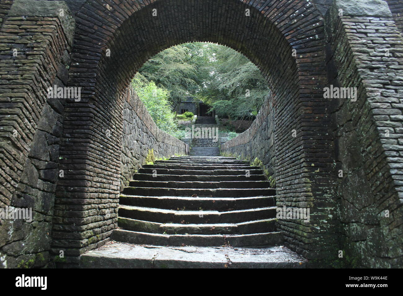 Bild eines alten Stein tunnel Arch und Treppe vor Bäumen und einem kleinen Gebäude im Rivington Pike Stockfoto