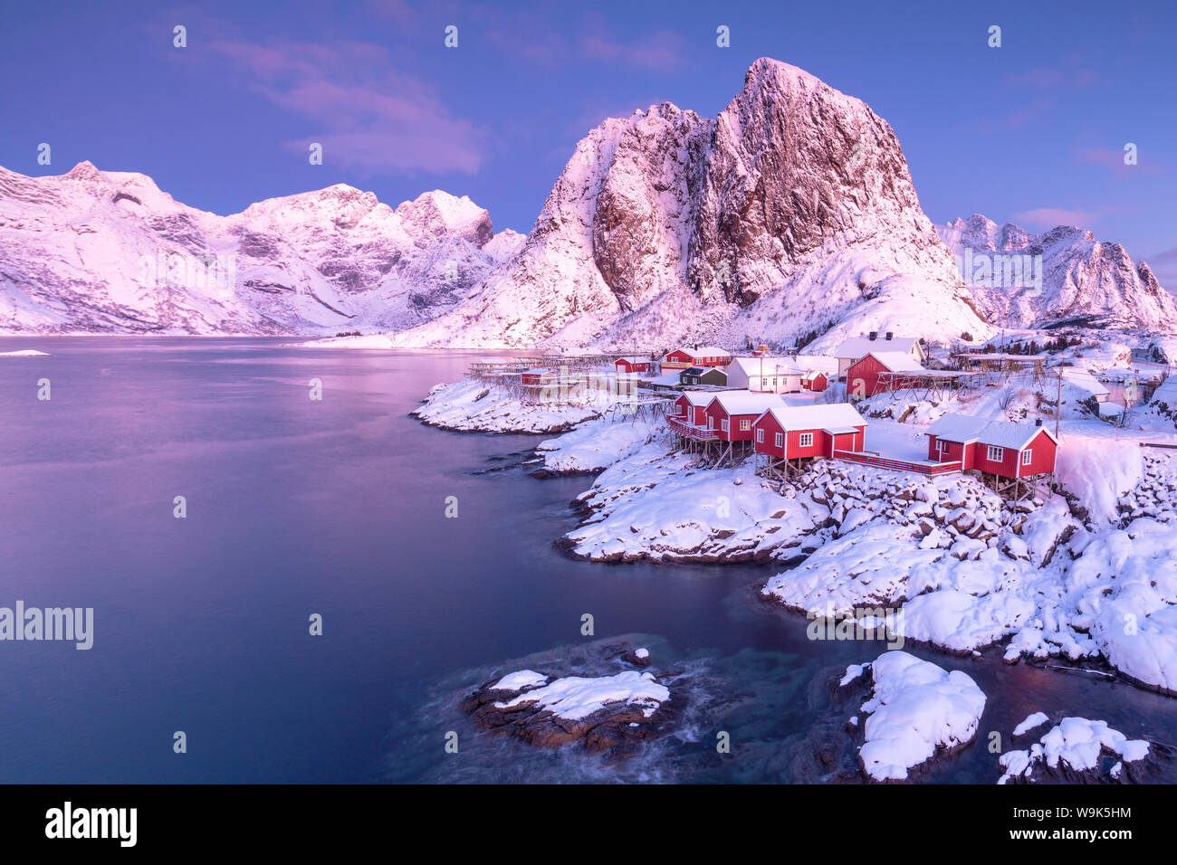 Rosa Sonnenaufgang auf schneebedeckten Gipfeln durch das gefrorene Meer rund um das Dorf von Hamnoy, Nordland, Lofoten, Arktis, Norwegen, Skandinavien, Europa umgeben Stockfoto