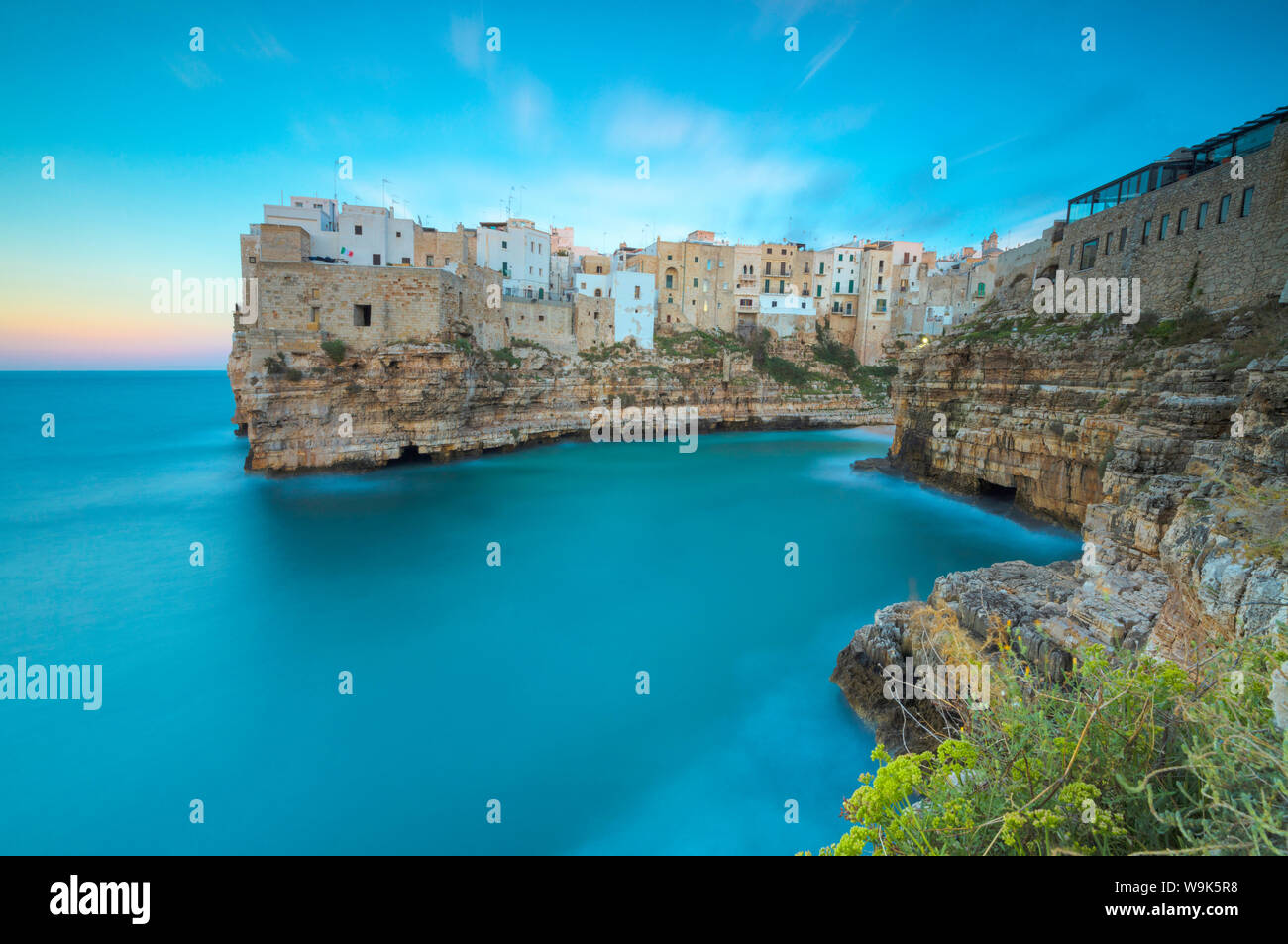Das türkisfarbene Meer bei Sonnenuntergang durch die Altstadt auf den Felsen thront gerahmt, Polignano a Mare, in der Provinz Bari, Apulien, Italien, Europa Stockfoto