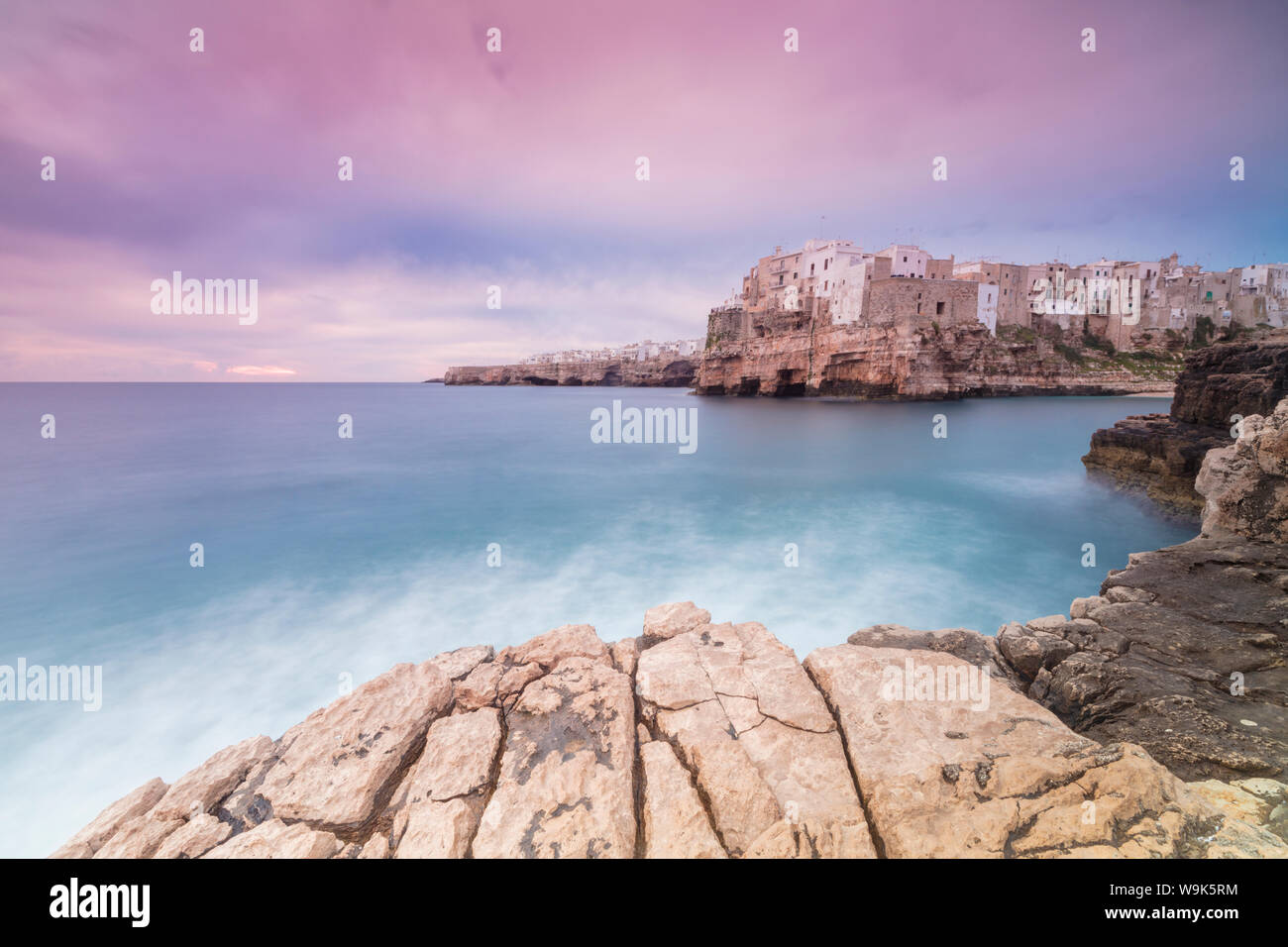 Rosa Sonnenaufgang auf dem türkisblauen Meer durch die Altstadt auf den Felsen thront gerahmt, Polignano a Mare, in der Provinz Bari, Apulien, Italien, Europa Stockfoto