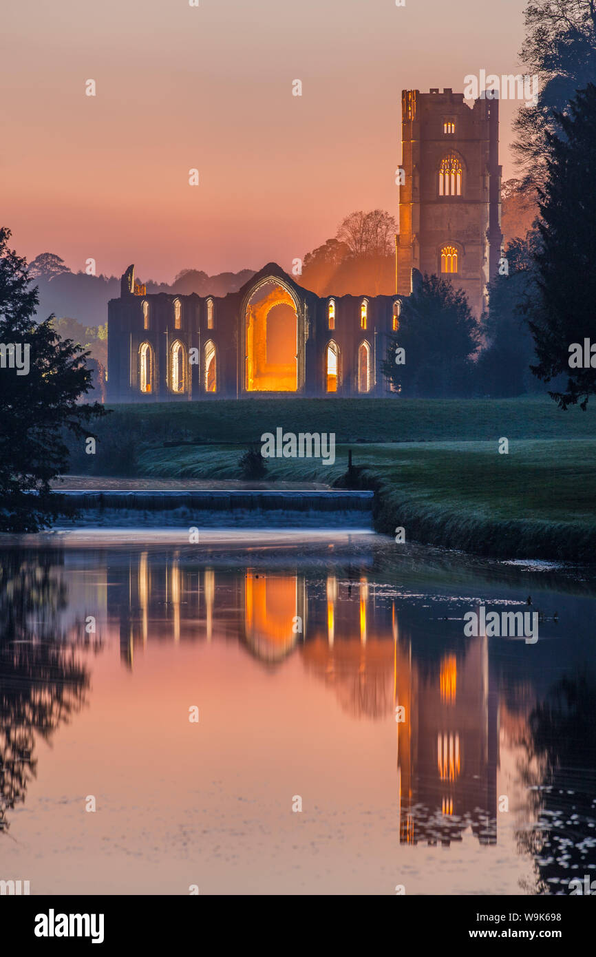 Das Zisterzienserkloster von Fountains Abbey leuchtet in der Dämmerung und in den Fluss Skell, UNESCO, North Yorkshire, Yorkshire, England, UK wider Stockfoto