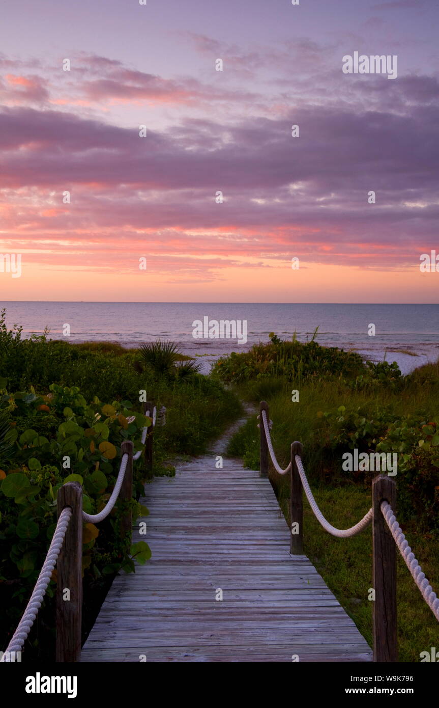 Ein Holzsteg über Sanddünen und tropischer Vegetation an den Strand bei Sonnenaufgang führende, Sanibel Island, Florida, Vereinigte Staaten von Amerika, Nordamerika Stockfoto