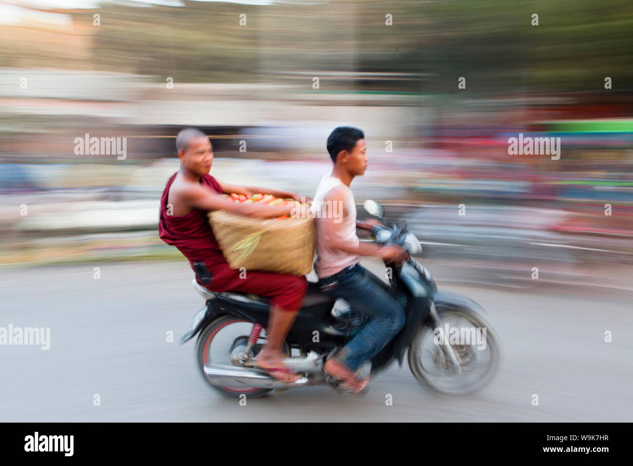 Geschwenkt und verschwommenes Bild erzeugen ein Gefühl von Bewegung, buddhistischer Mönch, sozius und Gemüse auf der Rückseite eines Mopeds, Mandalay, Myanmar Stockfoto