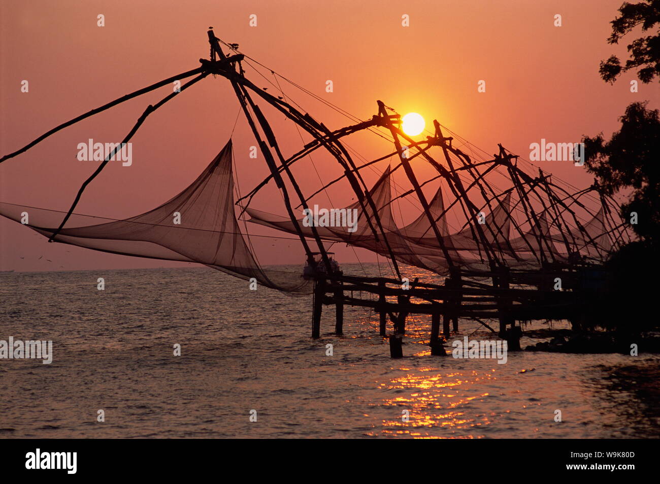 Eine Linie der chinesischen Fischernetze an der Küste bei Sonnenuntergang, Fort Cochin, Kerala, Indien, Asien Stockfoto