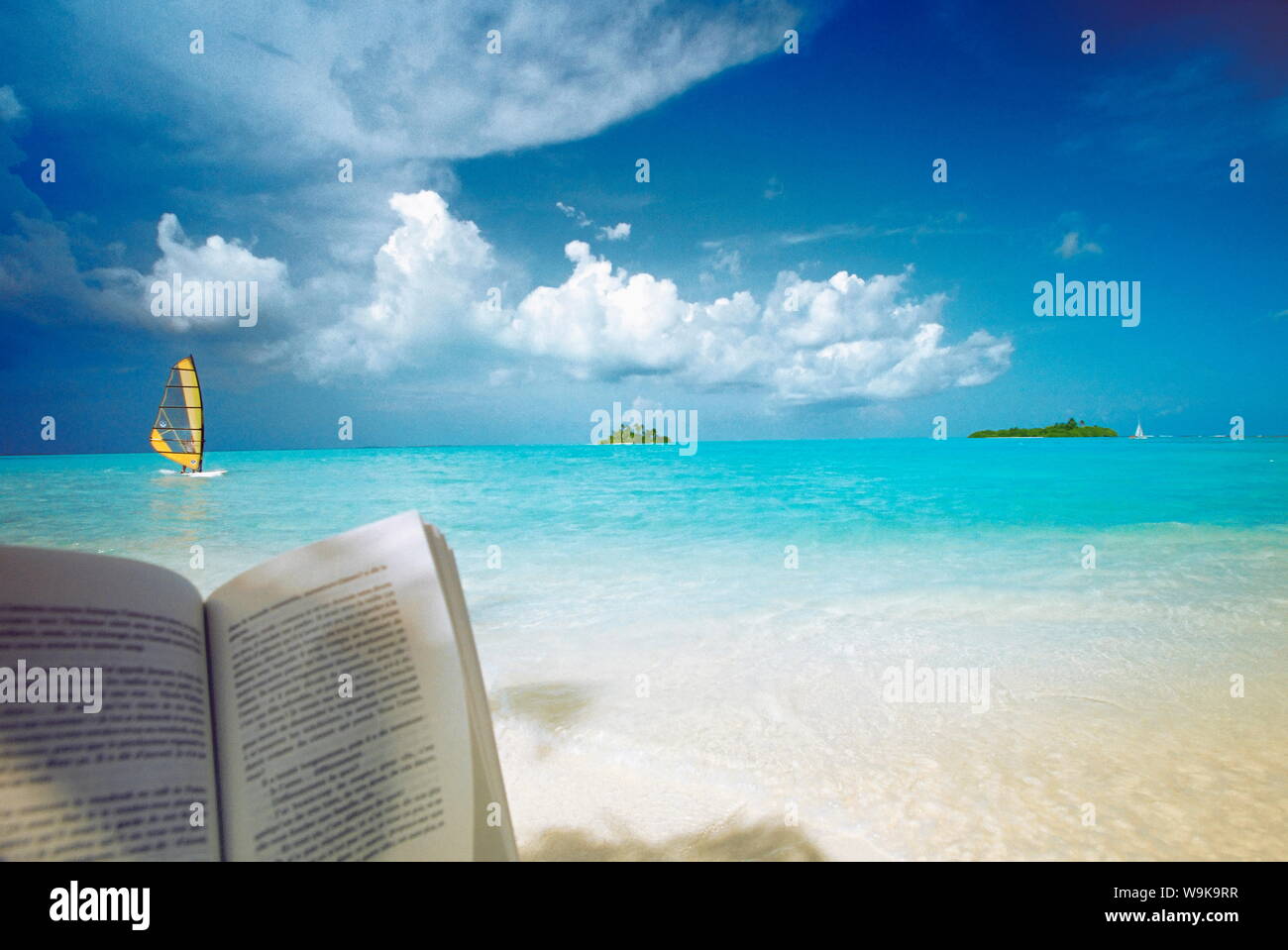 Lesen Buch am Strand, Windsurfen und Inseln in der Ferne, auf den Malediven, Indischer Ozean Stockfoto