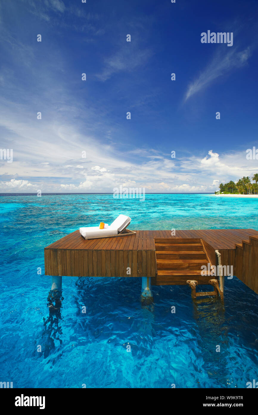 Sonnenliege und Steg in der blauen Lagune auf der tropischen Insel, Malediven, Indischer Ozean, Asien Stockfoto