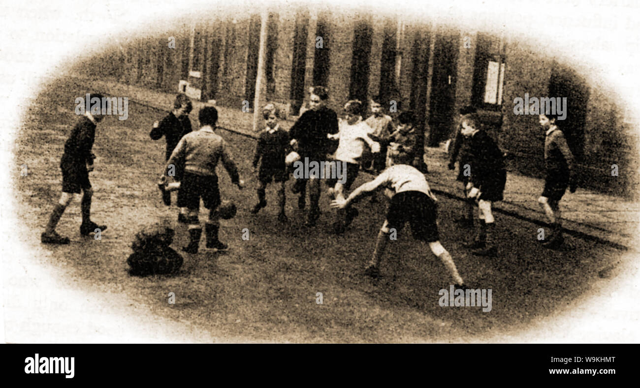 Circa 1940 - Britische Schule Kinder aus dem Norden Englands spielen Fußball auf der Straße Stockfoto