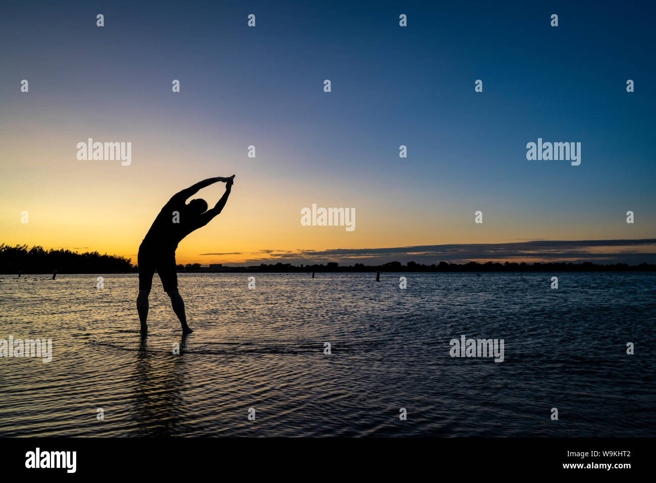 Yoga Palm Tree pose - Sonnenaufgang Silhouette eines Mannes auf einem See Strand, Boyd Lake State Park im Norden von Colorado Stockfoto