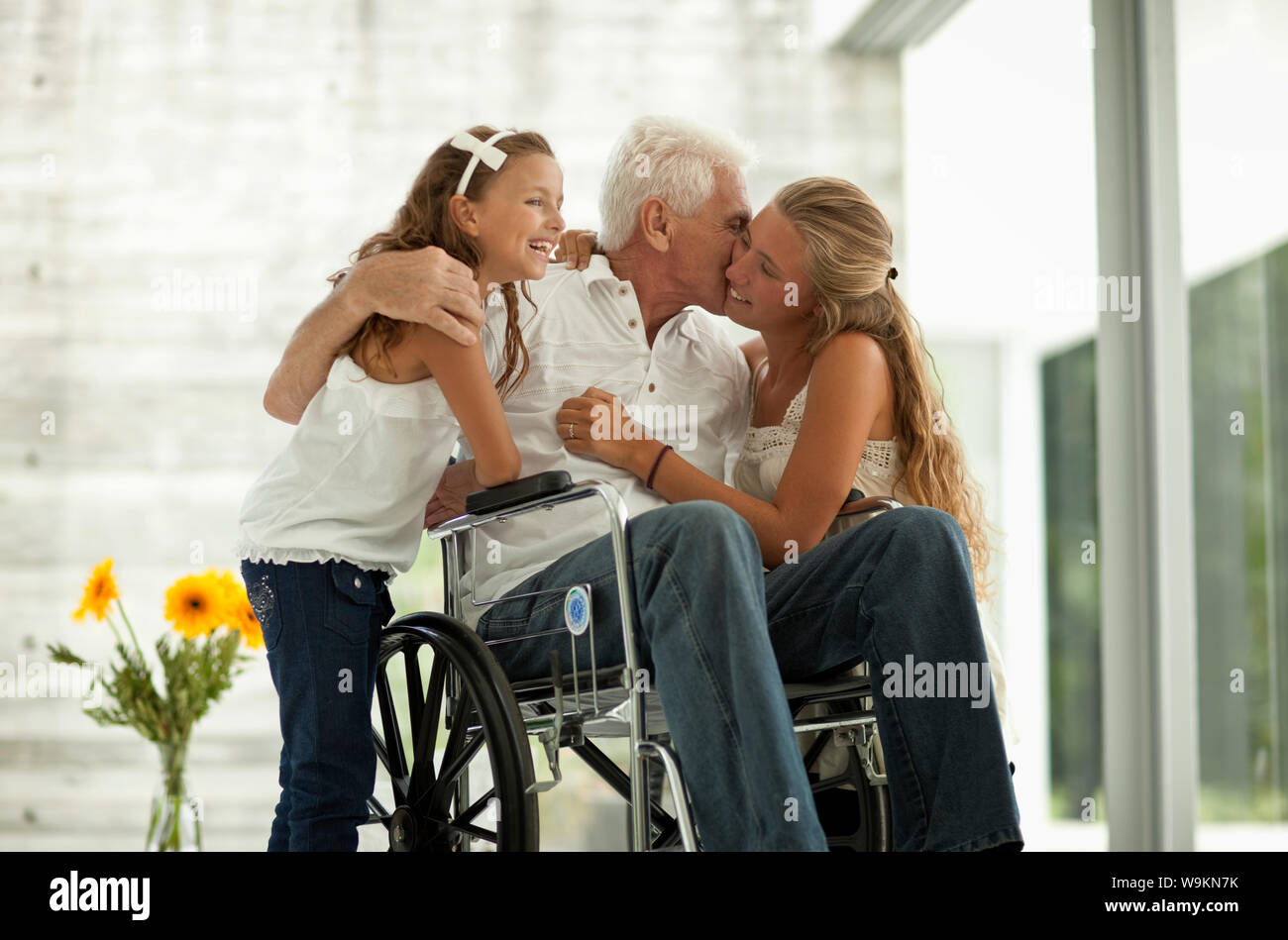 Älterer Mann im Rollstuhl, Gruß seine Enkelinnen. Stockfoto