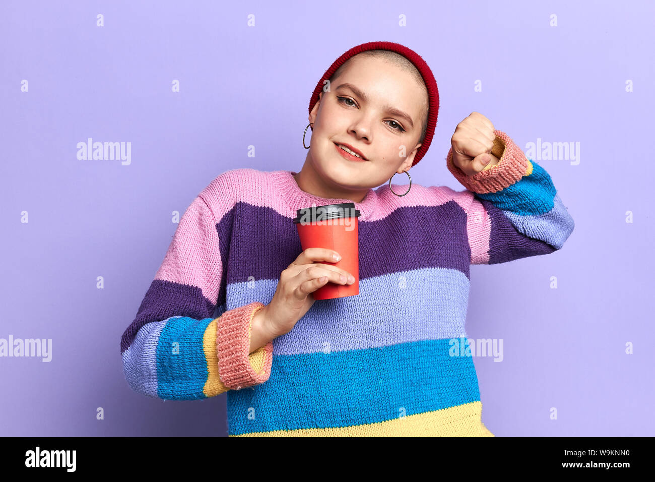 Schläfrige Mädchen in bunten stiped Pullover ihre Arme mit einer Tasse Kaffee am Morgen ausdehnen. Bis schließen Foto.studio erschossen. Lifestyle, Freizeit. Stockfoto