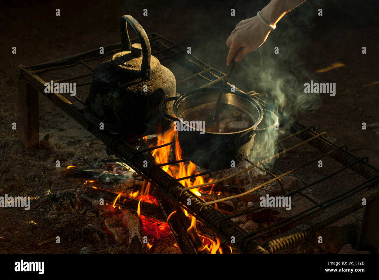 Ein Topf und ein Wasserkocher stehen über einem Feuer auf einem tragbaren Ofen aus Metall Stangen in einem Nomad Wohnung Stockfoto
