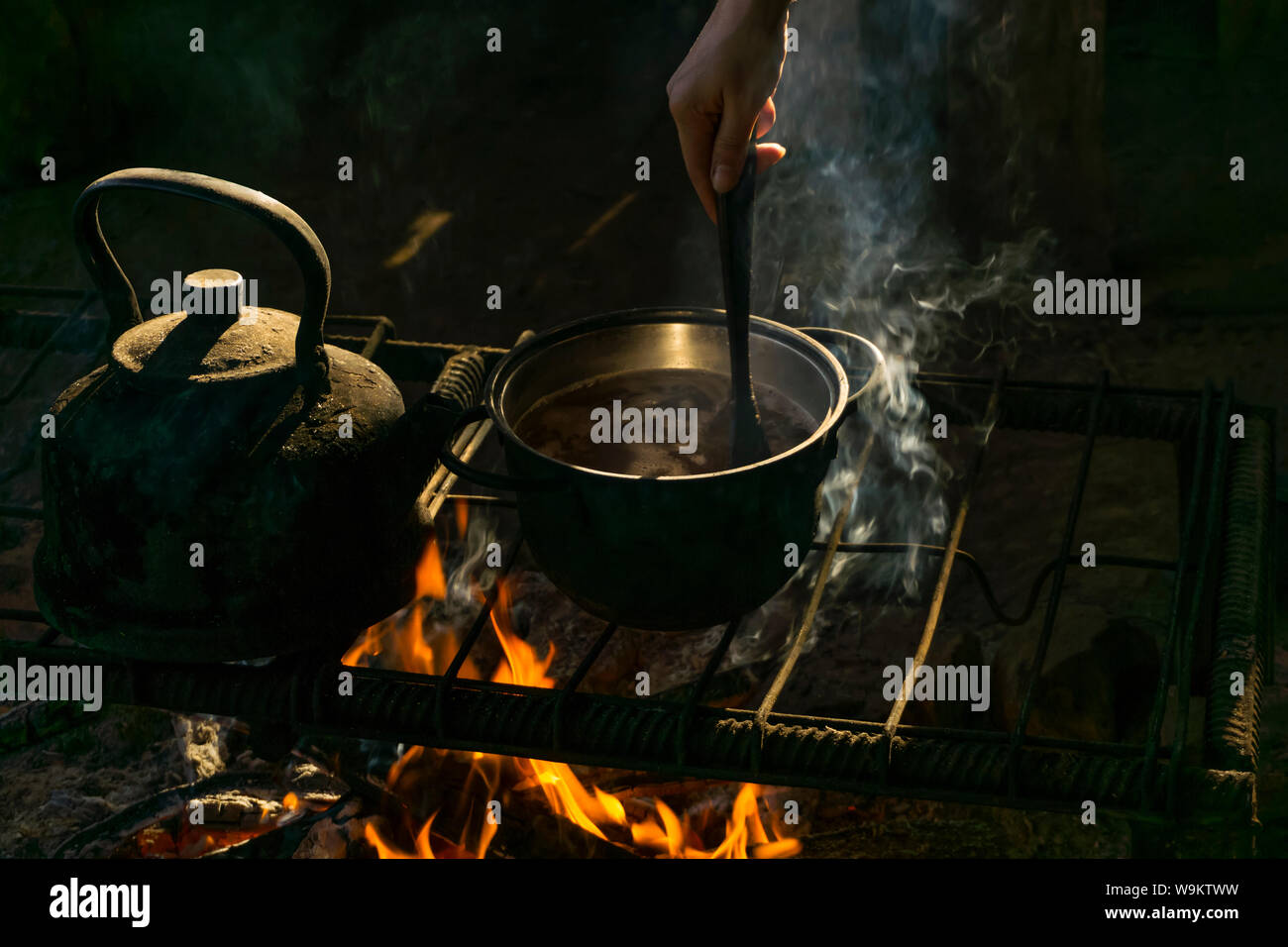 Topf und Wasserkocher stand über einem Feuer auf einem tragbaren Ofen aus Metall Stangen in einem Nomad Wohnung Stockfoto