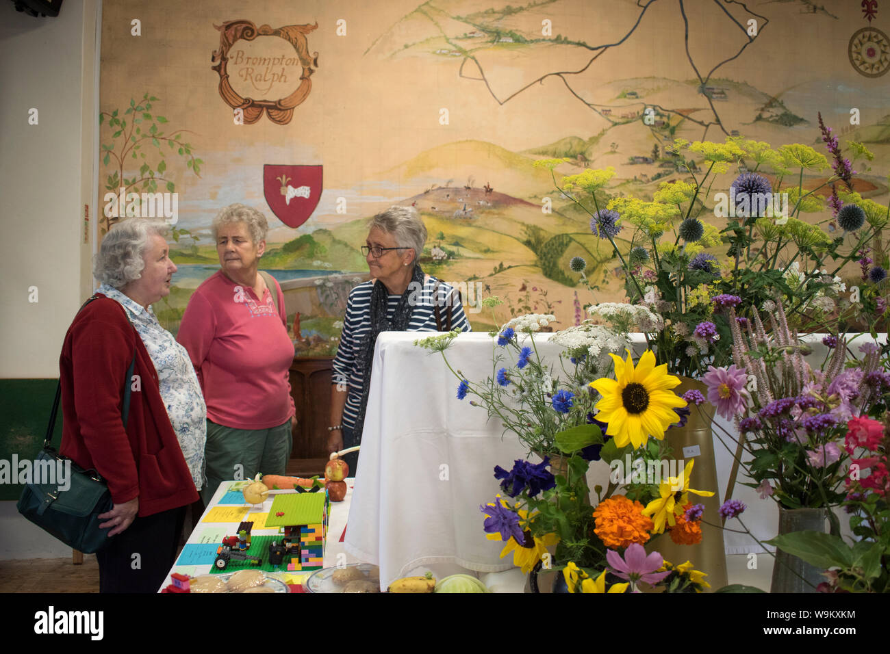 Dorf Flower Show 2010 s UK. Älteren Damen Frauen an einem Community Event Brompton Ralph, Somerset 2019. Malerei auf der Village Hall Wand ist von ihrer Gemeinschaft im Westen Land England HOMER SYKES Stockfoto