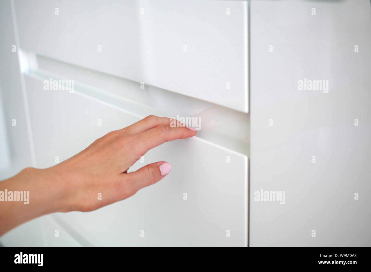 Frau Hand öffnet sich moderne Tür weiße Küche mit den versteckten Griff Stockfoto