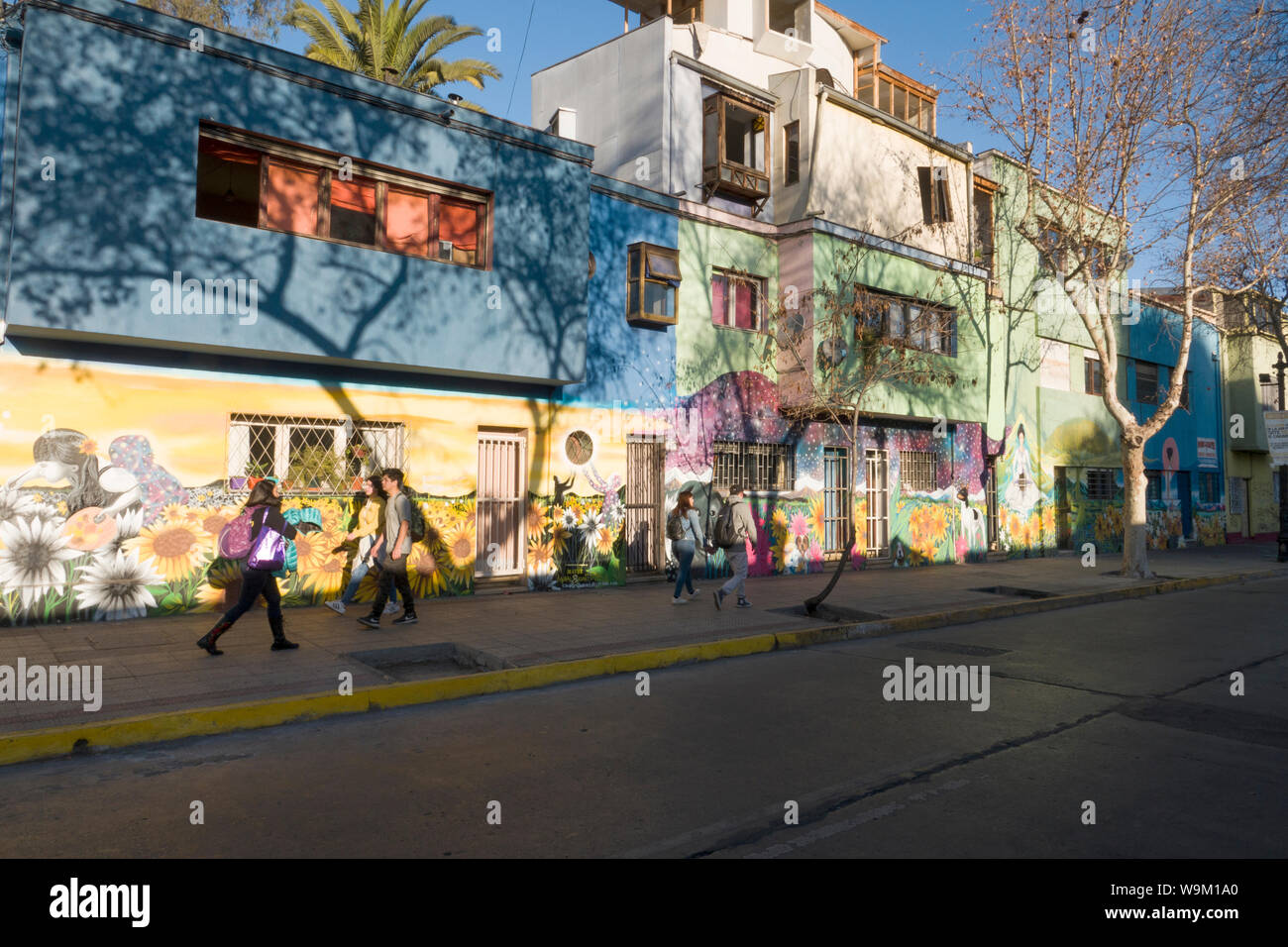 Fußgänger vorbei an Wandmalereien an Holzbauten in Bellavista, Santiago, Chile Stockfoto