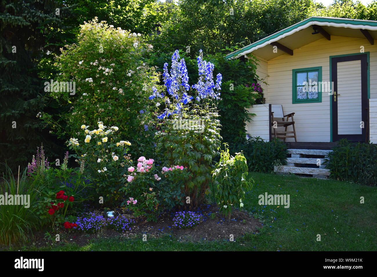 Ein Garten mit Gartenhaus, einen Stuhl und Blumen. Stockfoto