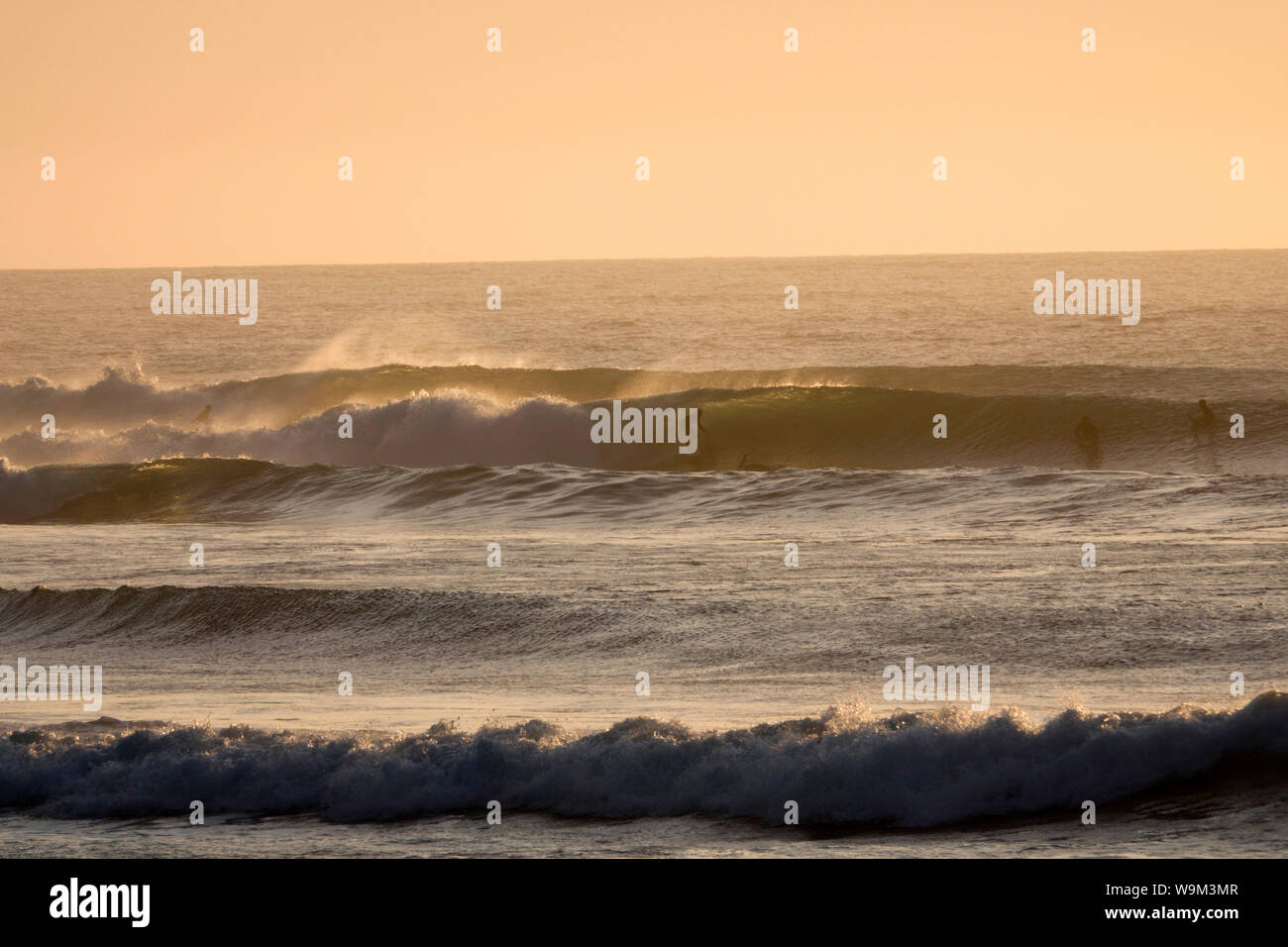 Surfer reiten Wellen an einem Point Break bei Sonnenuntergang in der Region Nuble, Chile Stockfoto