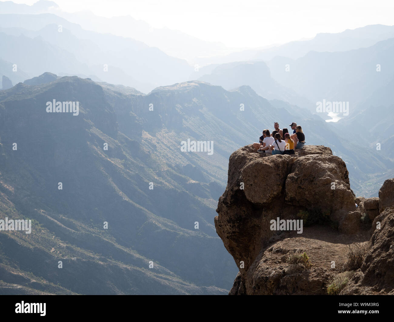 Sammeln Gruppe von jungen Erwachsenen Freunde auf einem Felsen in den Bergen am Roque Nublo, Gran Canaria übersehen Stockfoto