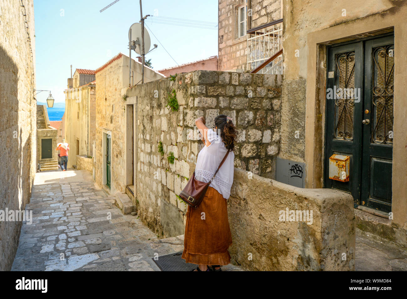 Eine Frau nimmt ein Foto innerhalb der alten Stadtmauern von Dubrovnik, Kroatien an einem sonnigen Sommertag Stockfoto