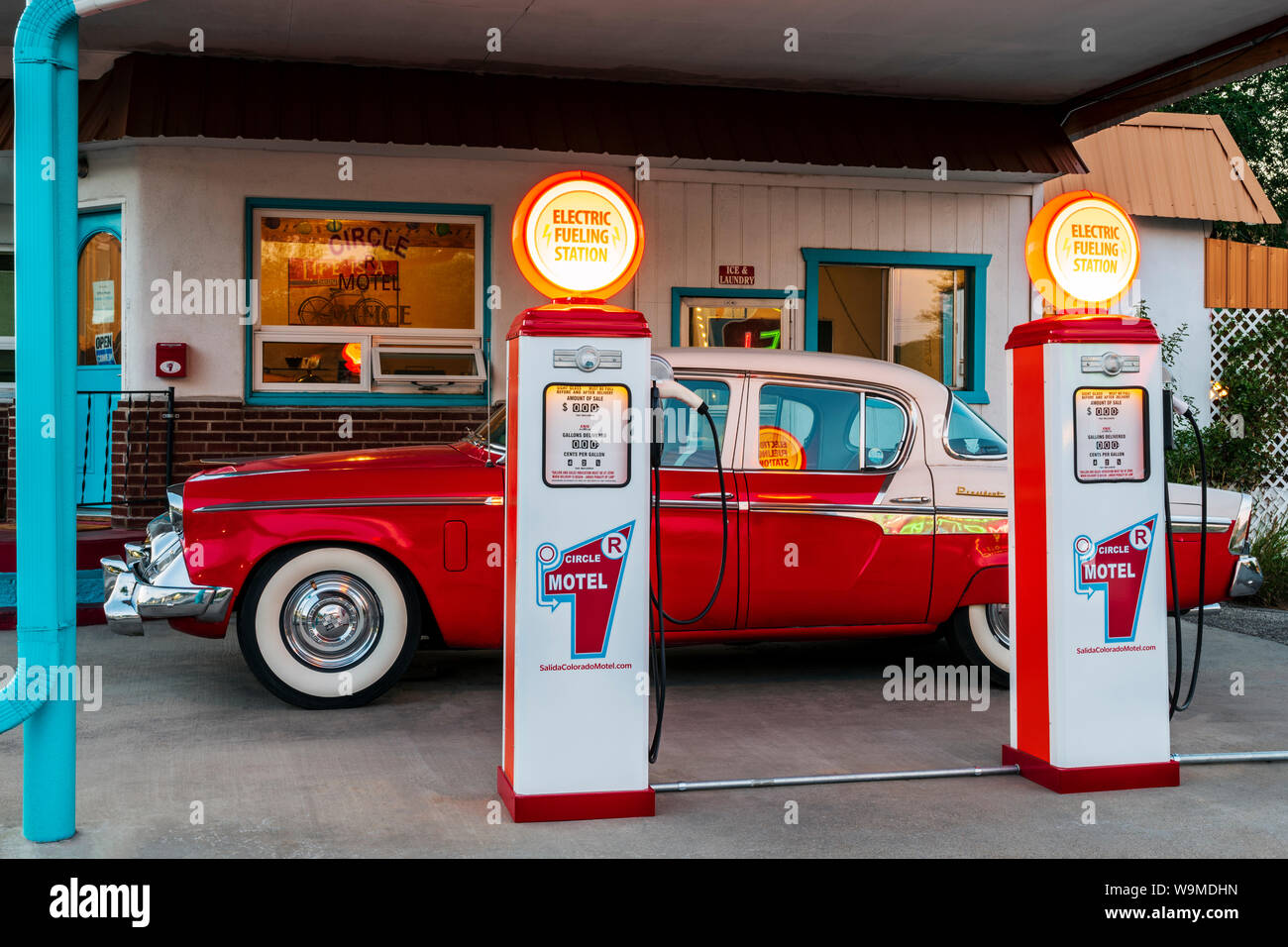 Dämmerung Blick auf 1955 Studebaker President classic car Vor antiken gas Pumpen elektrische Auto Ladegeräte konvertiert geparkt; den Kreis R Motel; Salida Stockfoto