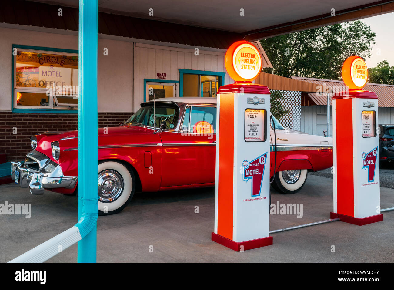 Dämmerung Blick auf 1955 Studebaker President classic car Vor antiken gas Pumpen elektrische Auto Ladegeräte konvertiert geparkt; den Kreis R Motel; Salida Stockfoto