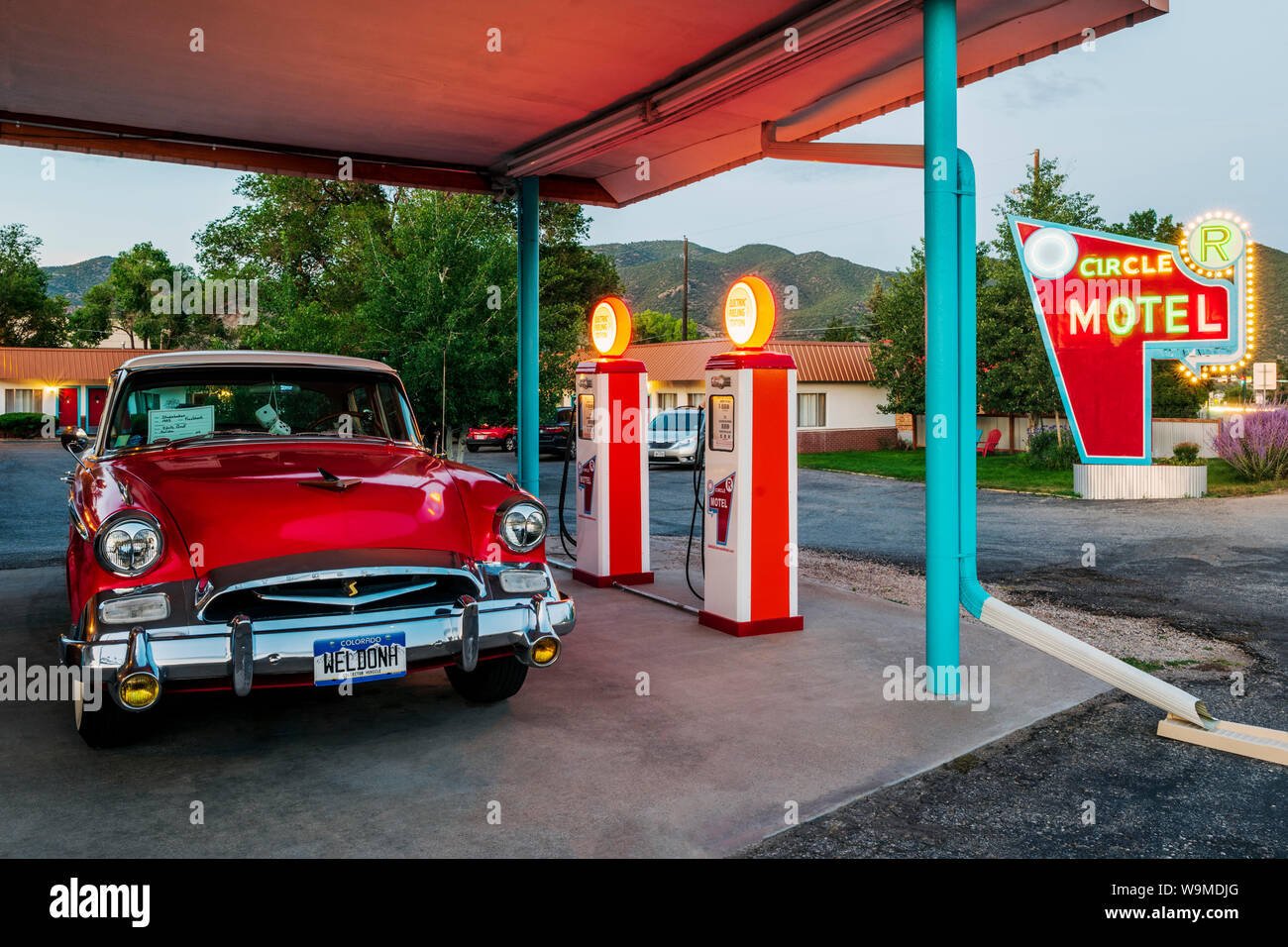 Dämmerung Blick auf 1955 Studebaker President classic car Vor antiken gas Pumpen elektrische Auto Ladegeräte konvertiert geparkt; den Kreis R Motel; Salida Stockfoto