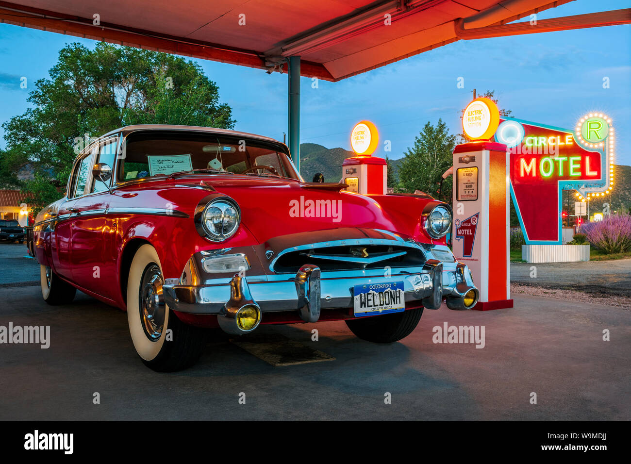 Dämmerung Blick auf 1955 Studebaker President classic car Vor antiken gas Pumpen elektrische Auto Ladegeräte konvertiert geparkt; den Kreis R Motel; Salida Stockfoto